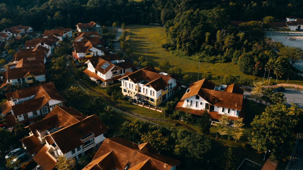 pexels-photo-1654330-1654330 Aerial view of suburban houses with red roofs surrounded by greenery at sunset.