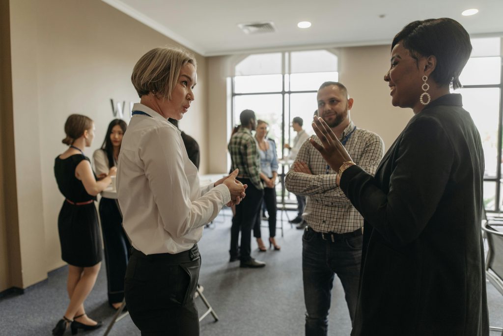 Professionals networking at a corporate event indoors, discussing and collaborating.